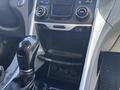 A gear shift of a 2014 Hyundai Sonata with a leather-wrapped handle and dashboard controls visible above it