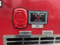 Close-up of a red electrical outlet and control panel on a 2006 E-One Typhoon featuring a battery monitor and block heater label