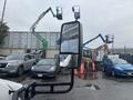 A 2021 Ford Transit-350 with a side mirror reflecting nearby vehicles and machinery in a parking lot