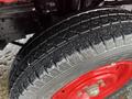 Close-up of a wet tire with a textured tread pattern mounted on a red steel wheel from a 2001 Toyota Dyna