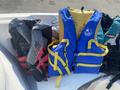 A red and black life jacket alongside a blue life jacket with yellow straps on a boat seat