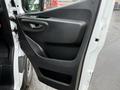 The interior door panel of a 2023 Mercedes-Benz Sprinter featuring a sleek black design with a handle and speaker area