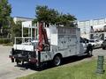 A 2013 Ford F-550 flatbed truck with utility compartments and a crane mounted on the rear side
