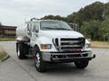 A white 2013 Ford F-750 truck with a tank attached at the back and a robust front grille and bumper