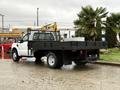 A white 2008 Ford F-350 flatbed truck with a black flatbed and a metal mesh fence on the back parked at a lot