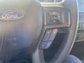 A close-up of a black steering wheel from a 2017 Ford F-150 featuring control buttons for volume and phone functions