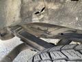 A close-up view of the underside of a 2023 GMC Savana showing a damaged area on the frame and a tire on the left side