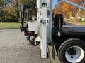 A 2011 International 7500 truck with a mounted hydraulic lift system featuring a control panel and a spool of cable on the side