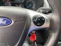 Close-up of a 2017 Ford Transit Connect steering wheel with a focus on the Ford logo and control buttons including the cruise control and phone features