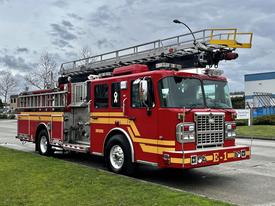 A red 2009 Spartan Gladiator fire truck with a ladder on top and yellow accents parked on a street