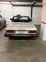 A white 1982 Mercedes-Benz 380 convertible parked with its top down showcasing a sleek design and rear features including distinctive taillights and branded badge