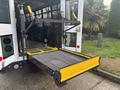 A 2021 Ford Transit-350 with a deployed wheelchair lift featuring a metal platform and yellow safety markings