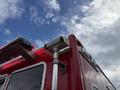 A red 2007 Ford F-550 with a light bar and a mounted spotlight on the side