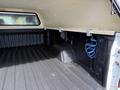 Interior of a 2019 Chevrolet Silverado 1500 truck bed with a fitted cap and a textured floor liner showcasing hooks and a coil of blue wire