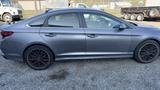 A 2018 Hyundai Sonata in gray with black alloy wheels parked on gravel