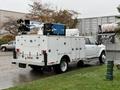 A white 2024 RAM 5500 truck equipped with a utility body and mounted equipment including a boom lift and a generator on the back
