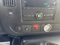 The dashboard of a 2018 Chevrolet Express featuring a digital clock a radio control panel and a gauge next to a stop request button