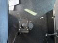 A black control box with a round knob and connectors visible on a carpeted floor inside a vehicle