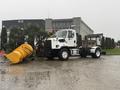 A 2016 Freightliner 108SD truck equipped with a yellow snow plow attachment in the foreground