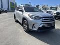A silver 2018 Toyota Highlander with a black grille and alloy wheels parked with its front angled towards the viewer