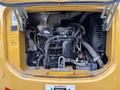 The engine compartment of a 2017 John Deere 50G showing various components including hoses wires and a cooling fan