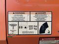 A warning label on a JLG 660SJ indicating tip-over hazards and load capacity of 500 lbs with safety instructions related to operation and restrictions