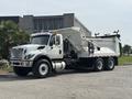 A 2013 International WorkStar truck with a white body and a large dump bed in the raised position, showcasing its heavy-duty construction and design