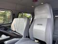 A 1999 Freightliner FL80 interior featuring gray leather seats with distinct stitching and the Freightliner logo visible on the driver’s seat
