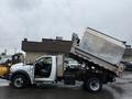 A 2011 Dodge Ram 5500 dump truck with a raised metal bed angled upwards displaying its dumping mechanism