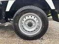 Close-up of a silver wheel from a 2010 Suzuki Carry featuring a black tire with a patterned tread and a central hub cap