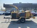 A yellow 2010 Vermeer Corporation BC1200XL wood chipper with a large chute and attached trailer hitch visible on the side