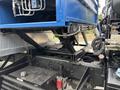 A 2017 Autocar Xpert truck's chassis detail showing a blue dump bed attachment and hydraulic lift system