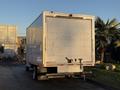 A 2015 GMC Savana cargo van with a white, flat-sided box trailer at the back and a hitch attached to the rear