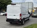 A white 2022 Ford Transit van with a high roof and large rear doors parked at an industrial area.