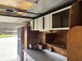 Interior view of a 2011 Workhorse W62 with metal cabinets and wooden shelves arranged for storage and workspace