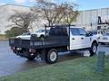 A 2020 Ford F-350 with a flatbed and a black mesh frame parked on a wet surface