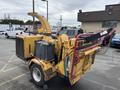 A yellow 2015 Vermeer Corporation BC1200XL wood chipper with a large hopper and a discharge chute, equipped with a gas tank and various controls