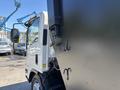 A white 2016 Isuzu NPR-HD truck with a partially open black cargo box revealing hooks attached to the side