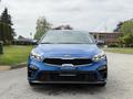 A blue 2021 Kia Forte is showcased with a front view highlighting its sleek design and distinctive grille