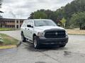 A white 2013 RAM 1500 pickup truck with a black front grille and chrome accents parked on a roadway