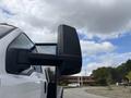 A white 2018 Ford F-750 truck with a large side mirror mounted on its driver's side