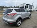 A silver 2014 Ford Escape parked with a rear view showing the hatchback and side profile