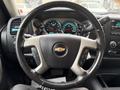 Steering wheel of a 2013 Chevrolet Silverado 3500HD with controls and dashboard gauges visible behind it