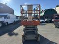 A 2010 Skyjack SJ scissor lift with a bright orange frame and platform, positioned for lifting, displaying labels and controls on the side