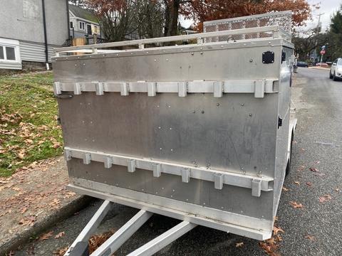 A metallic 2023 Express Customs trailer with a flat surface and metal latches on the sides designed for cargo transport