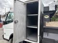 A 2015 Mitsubishi Fuso FE160 truck with an open metal storage compartment revealing two empty shelves inside