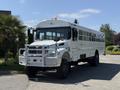 A white 2009 International 3000 CE school bus with a protective grille and tall tires is parked with its front facing the viewer