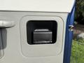 A blue and gray interior door handle of a 2013 Ford E-350 Super Duty featuring a rectangular recess for the handle and a textured grip area