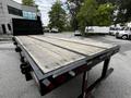 A 2011 International 4400 flatbed truck with a wooden deck and metal frame viewed from the rear angle