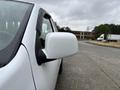 A 2011 Chevrolet Colorado with a white exterior and a side mirror covered in raindrops